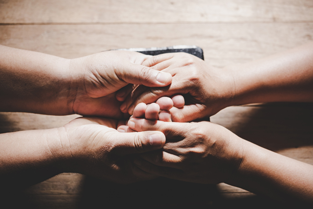 couple husband wife are holding hands pray together wooden table with copy space your